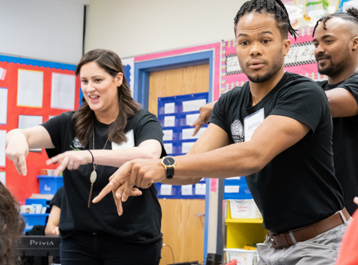 Two men and a woman perform a song in American Sign Language standing in a classroom.