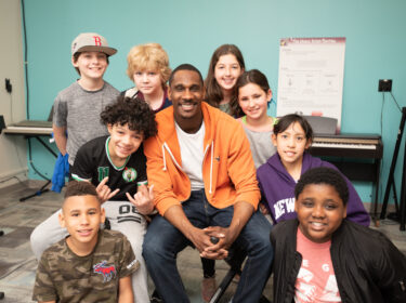 A group of students pose surrounding a man. 